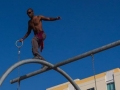 Dévyan with arms out, holding one ring, preparing to jump of the rings rig